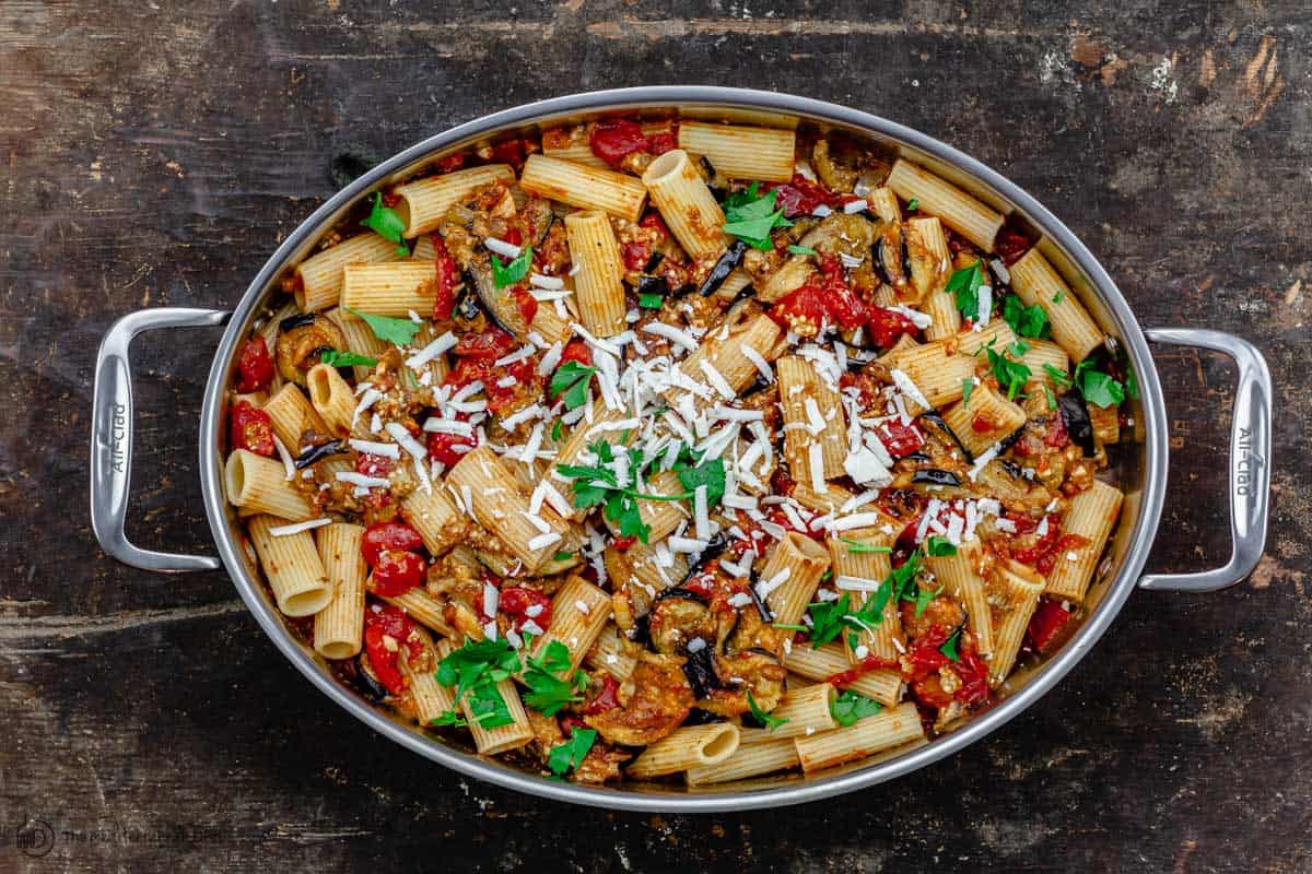 cooked pasta alla norma, finished with ricotta salata and fresh parsley in a pan