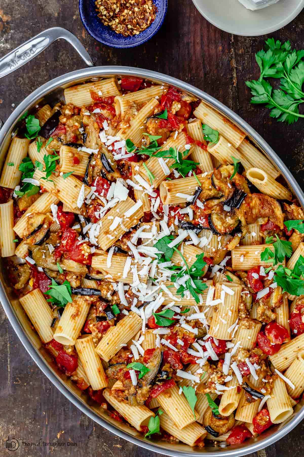 pasta alla norma in big pan with a side of crushed pepper flakes