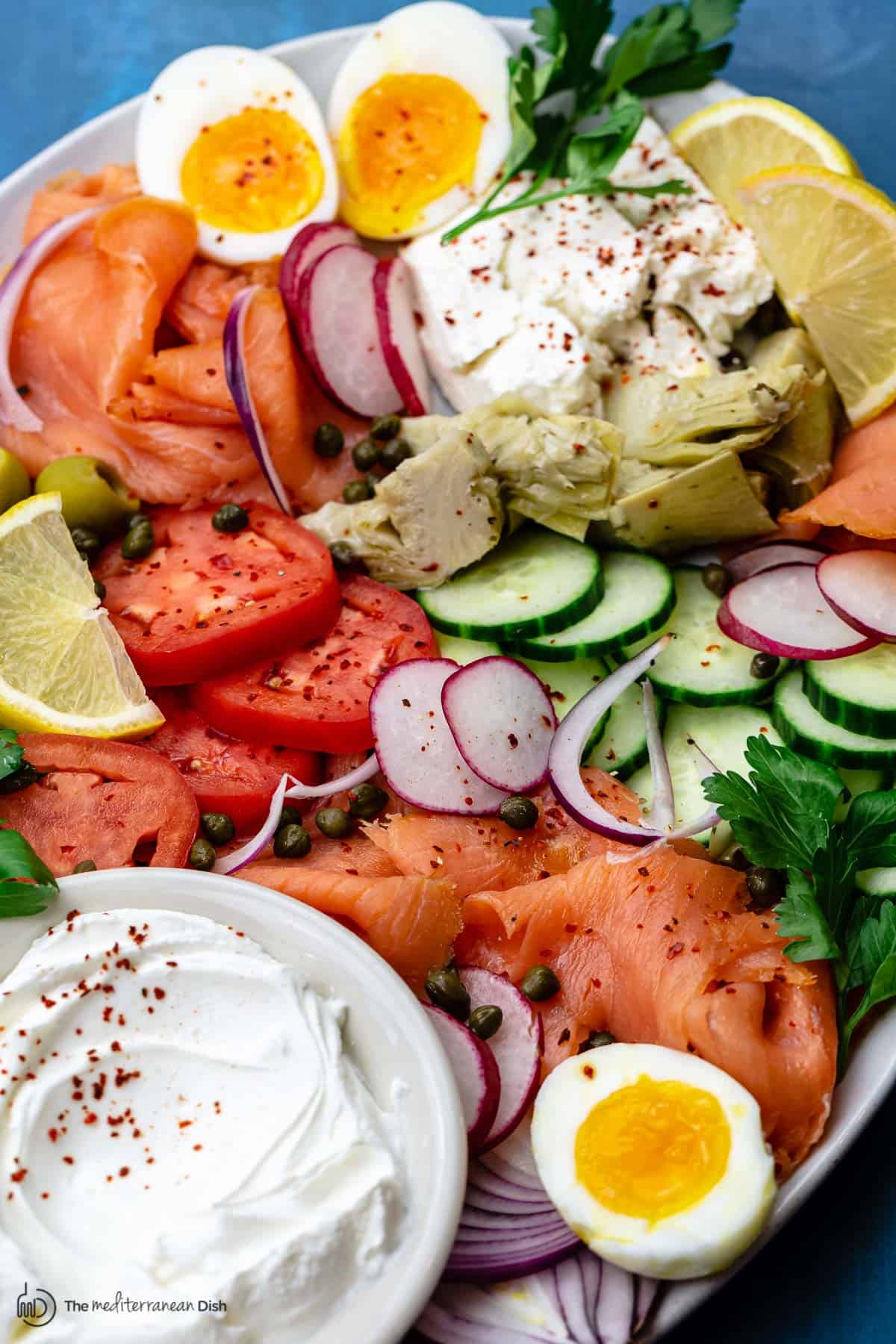 smoked salmon, fresh veggies, labneh cheese and eggs on a platter