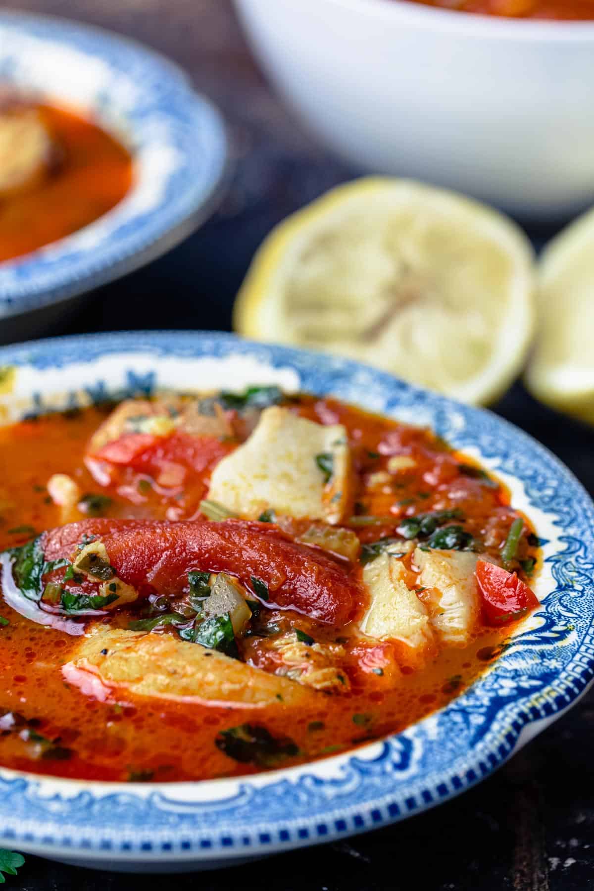 Bowls of Mediterranean Fish Soup with Lemon Wedges to the Side