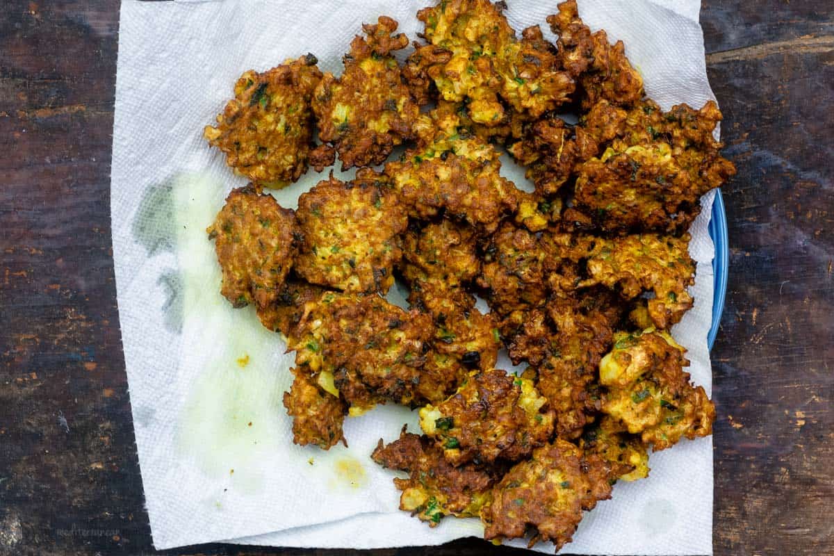 Cauliflower fritters resting on napkin to soak up excess oil