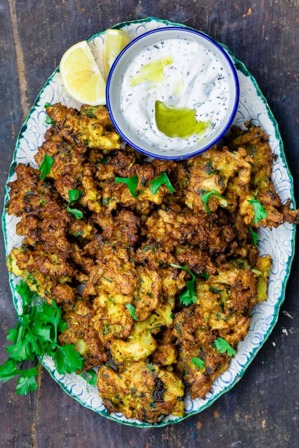 Cauliflower fritters served on a plate with dipping sauce