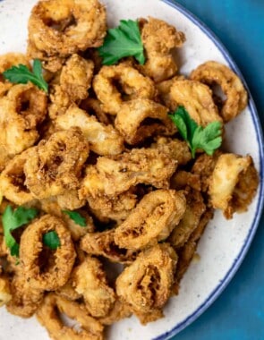 Fried calamari served on a plate atop a blue table