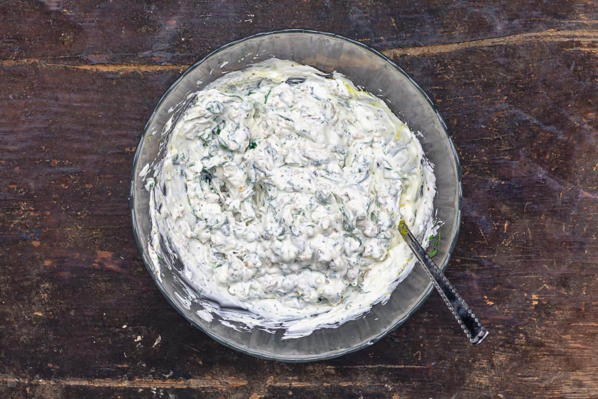 spinach is mixed with Greek yogurt, walnuts and spices in a big bowl