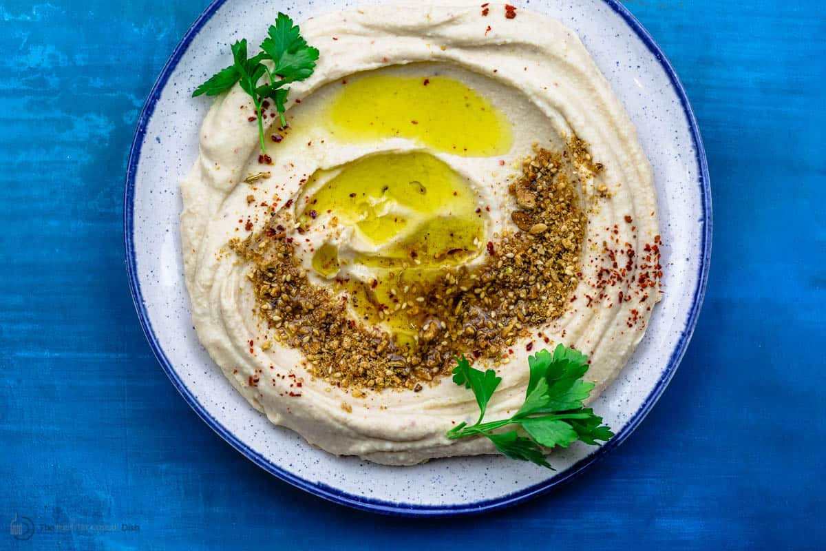 White bean hummus served in a plate with olive oil and dukkah