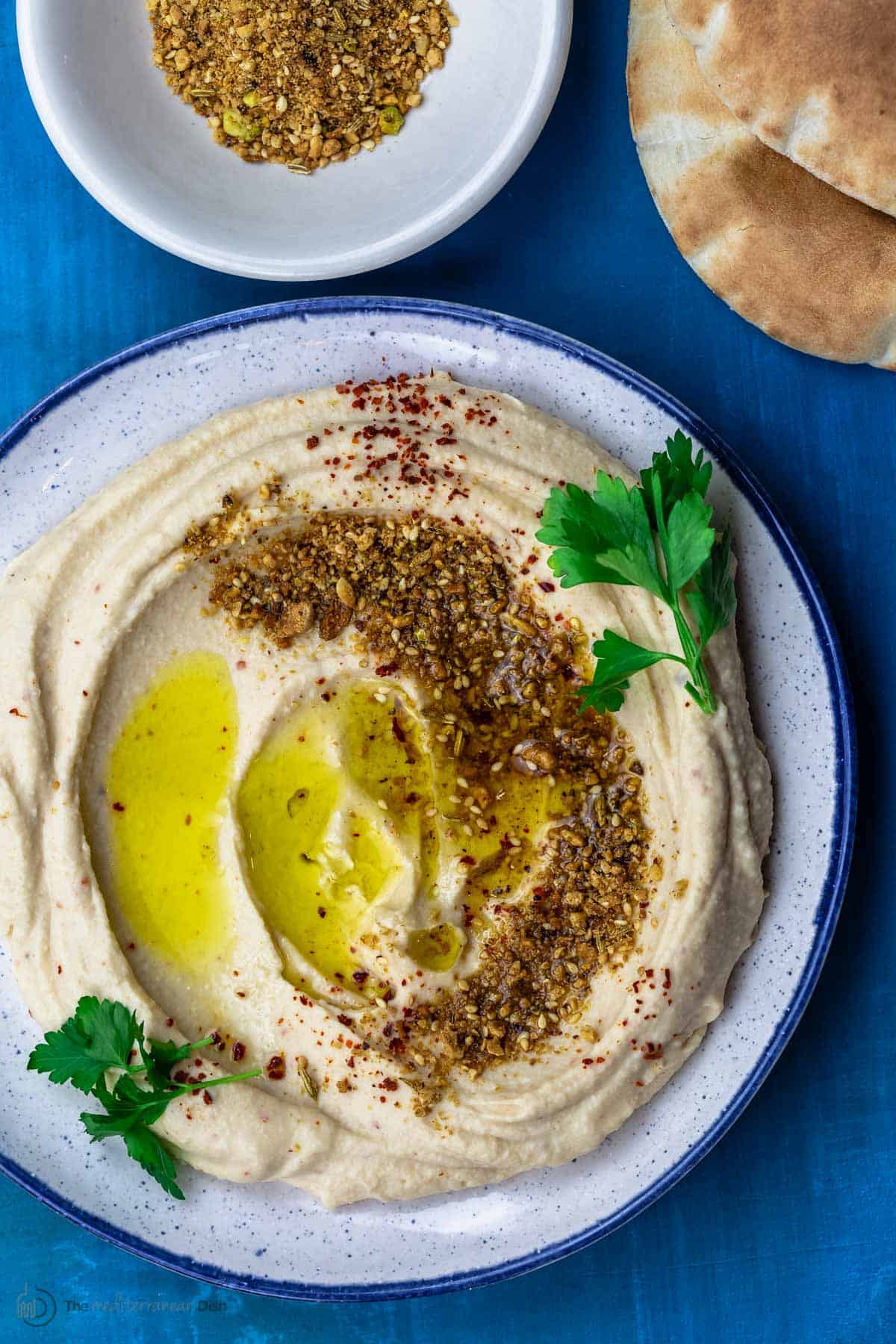 White bean hummus served in a plate and topped with dukkah and olive oil