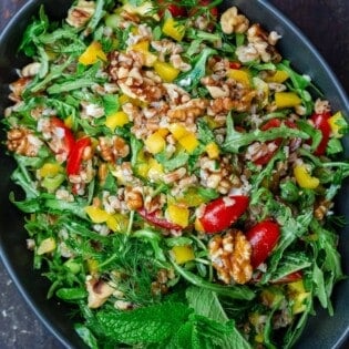 farro salad with arugula in a bowl mixed with walnuts and fresh vegetables