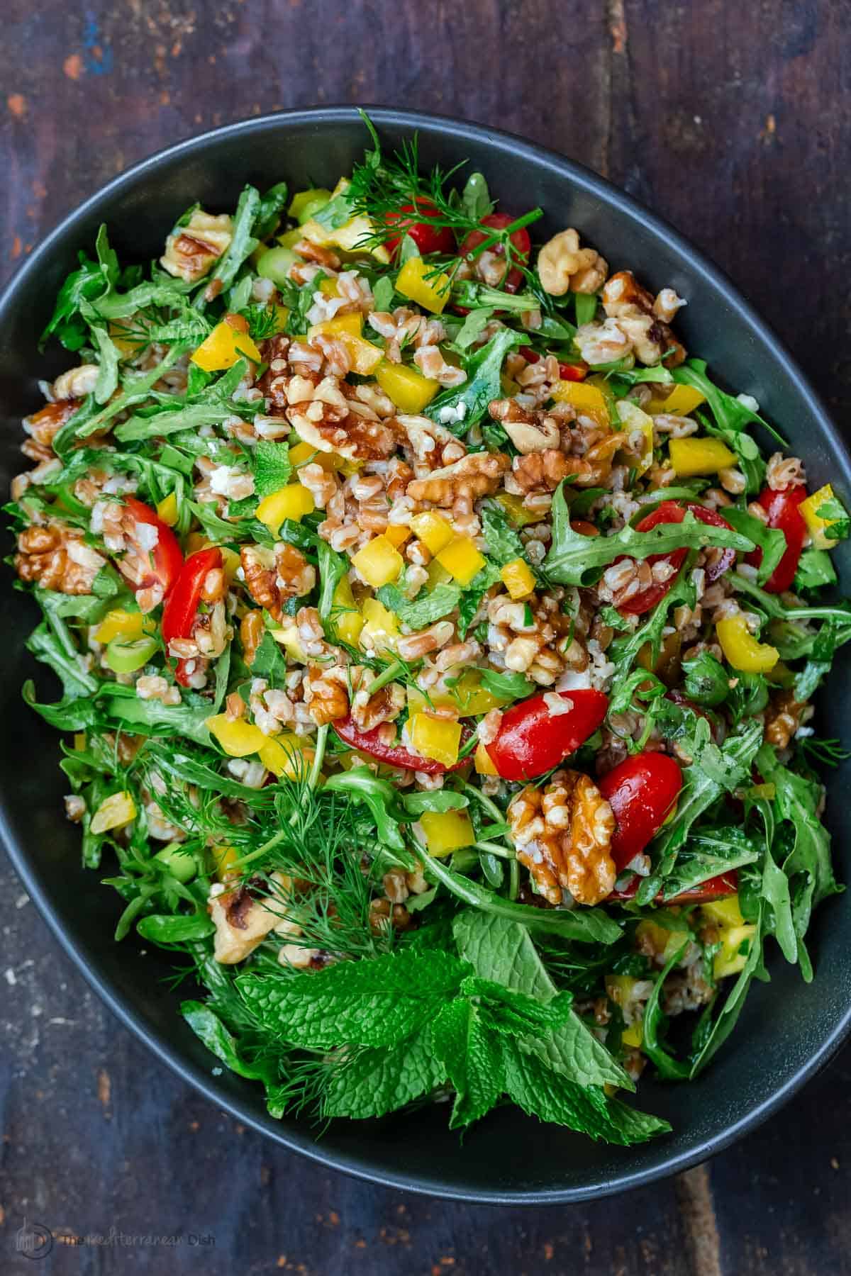 farro salad with arugula in a bowl mixed with walnuts and fresh vegetables