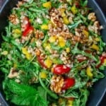 arugula and farro salad in a bowl mixed with walnuts and fresh vegetables