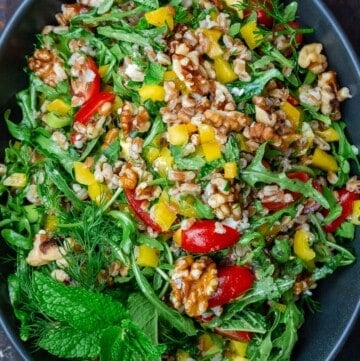 arugula and farro salad in a bowl mixed with walnuts and fresh vegetables