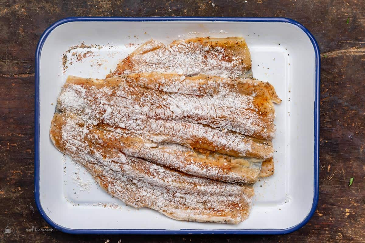 Fish fillets being dredged with flour