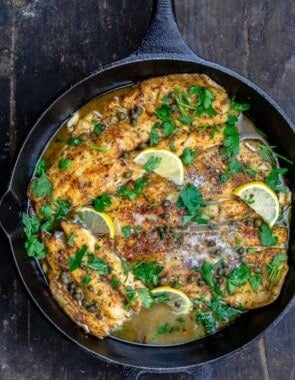 Pan-seared trout topped with a lemon piccata sauce in a cast iron skillet