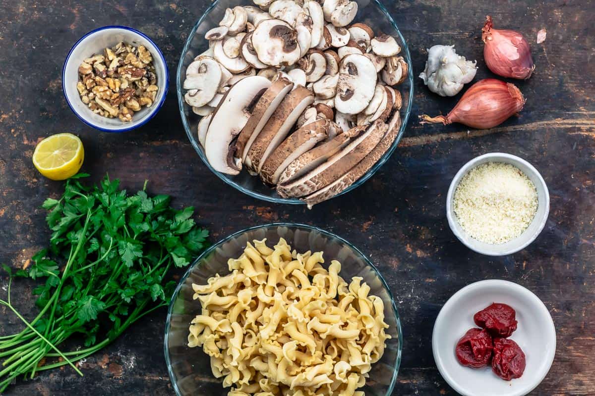 Ingredients including pasta, mushrooms, grated cheese, parsley, shallots, walnuts, and tomato paste