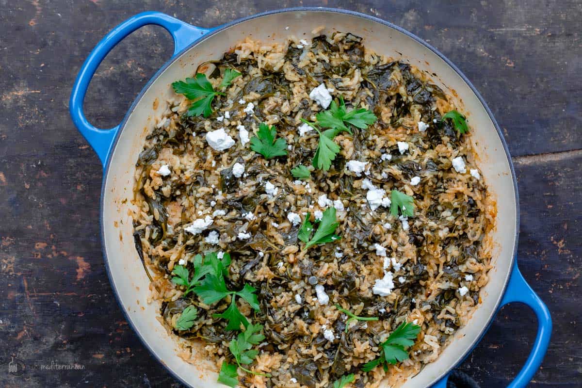 Spanakorizo in a pan topped with feta and parsley