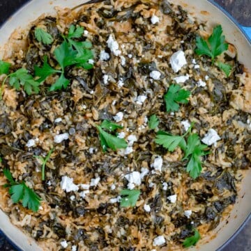 Greek spinach rice topped with feta and parsley in a pan