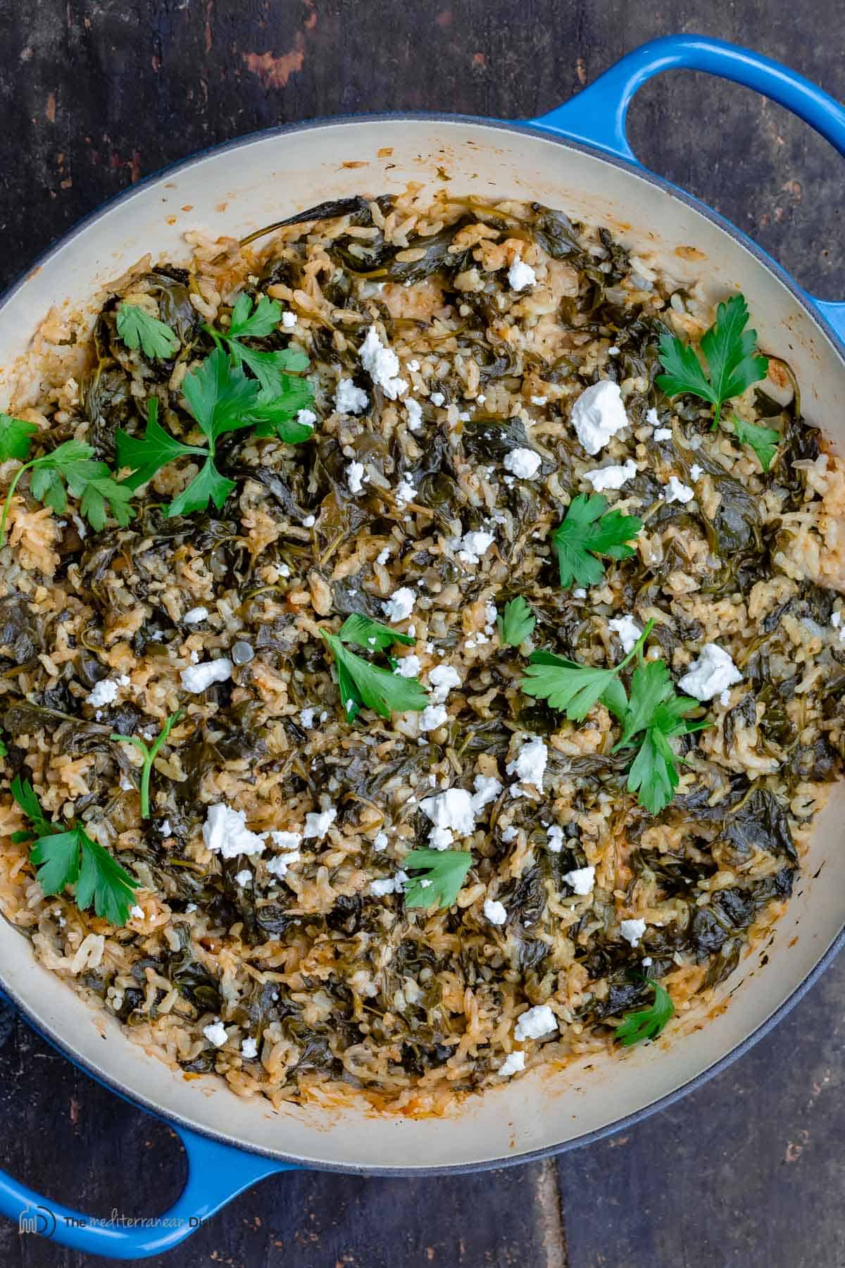 Greek spinach rice topped with feta and parsley in a pan