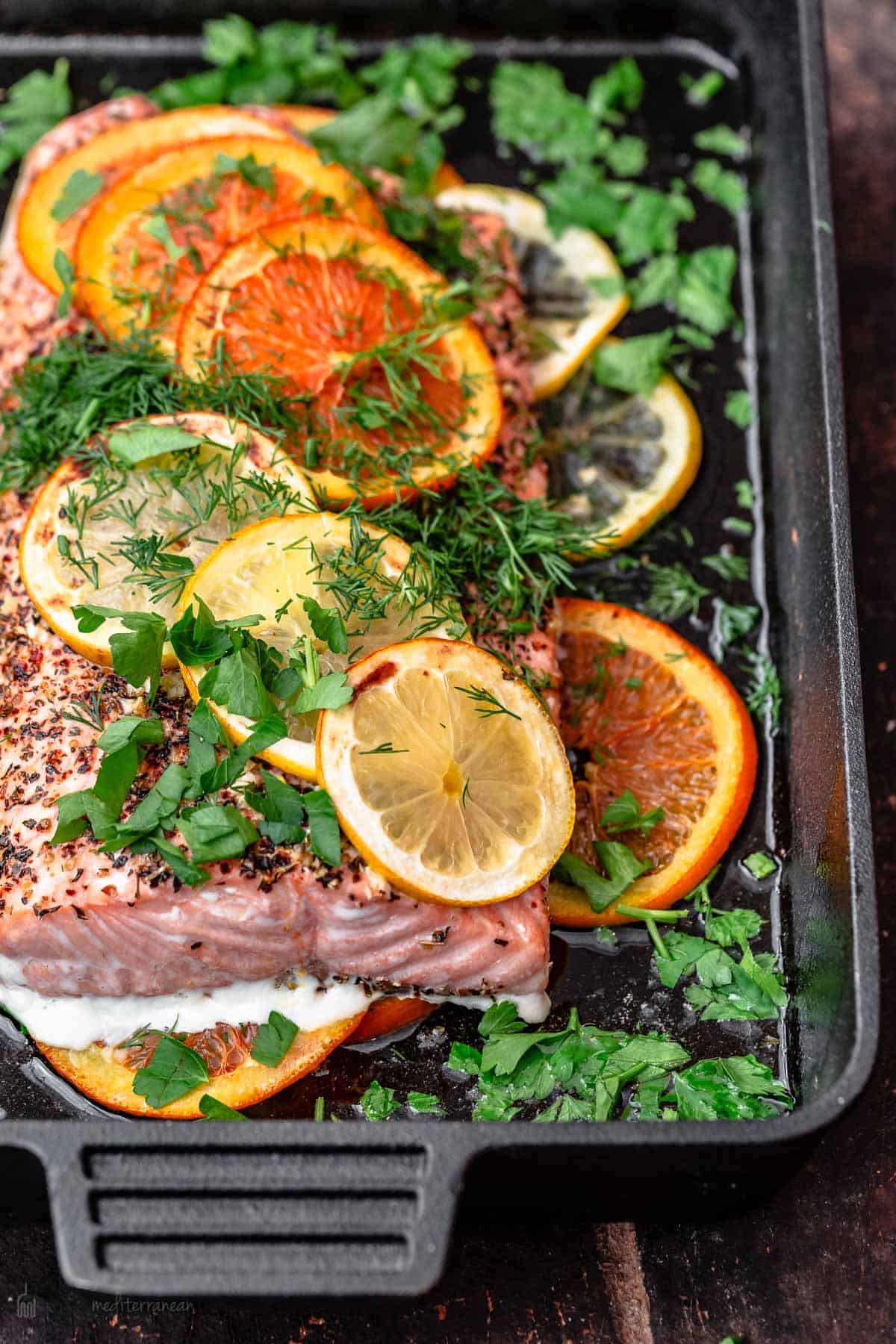 Salmon in cast iron skillet with slices of oranges