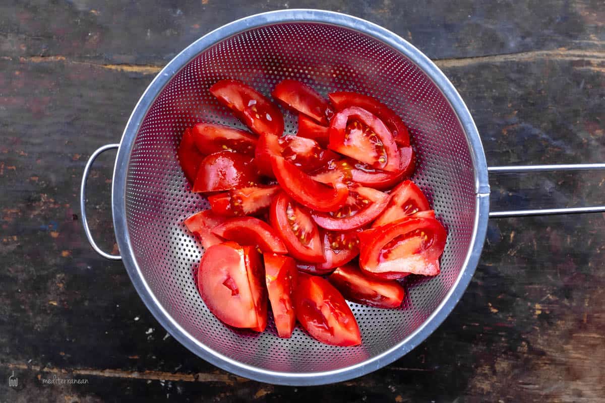 Slices of Tomato in a Metal Strainer with a Handle