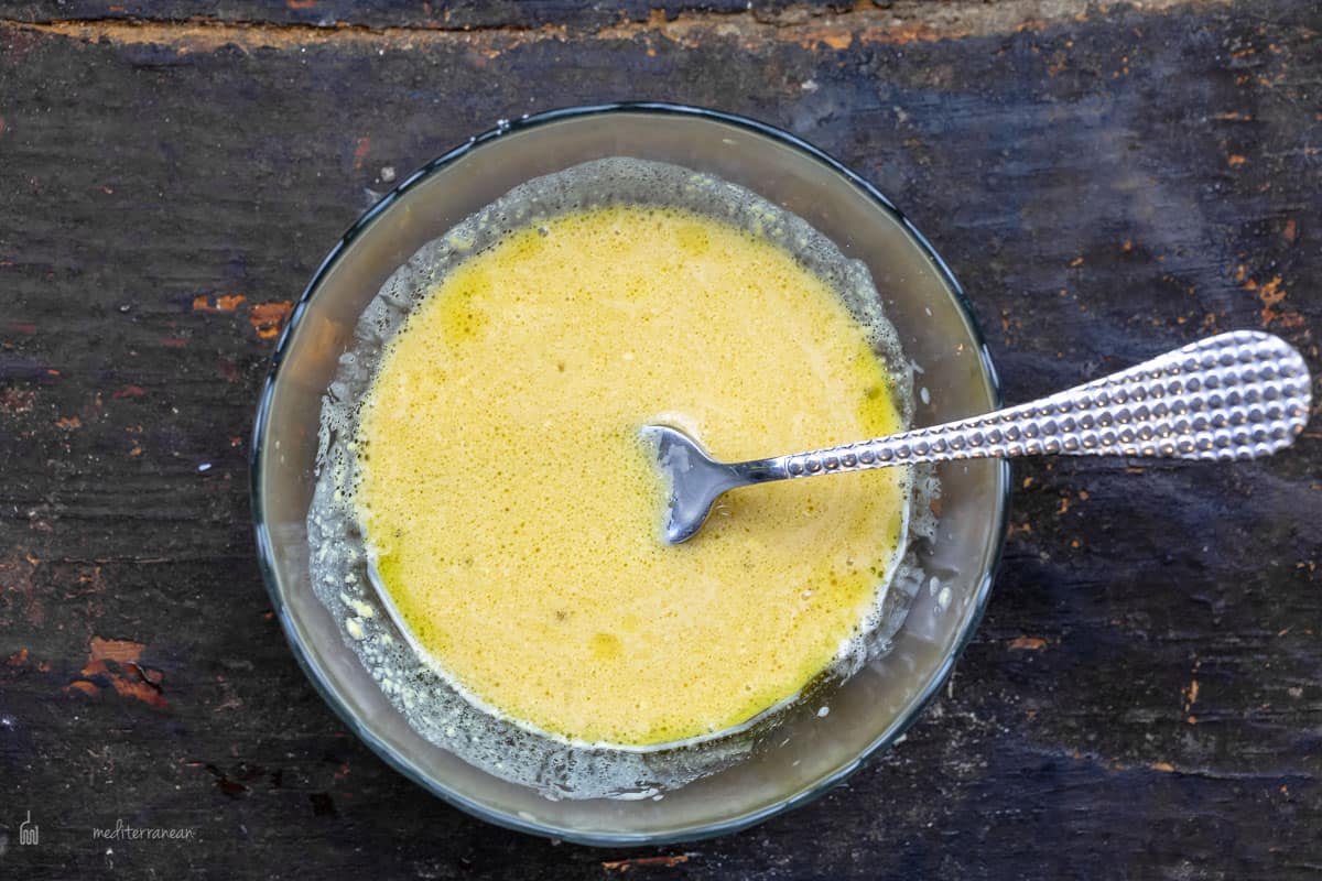 A Bowl of Dijon Mustard Dressing for Nicoise Tuna Salad with a Fork Inside