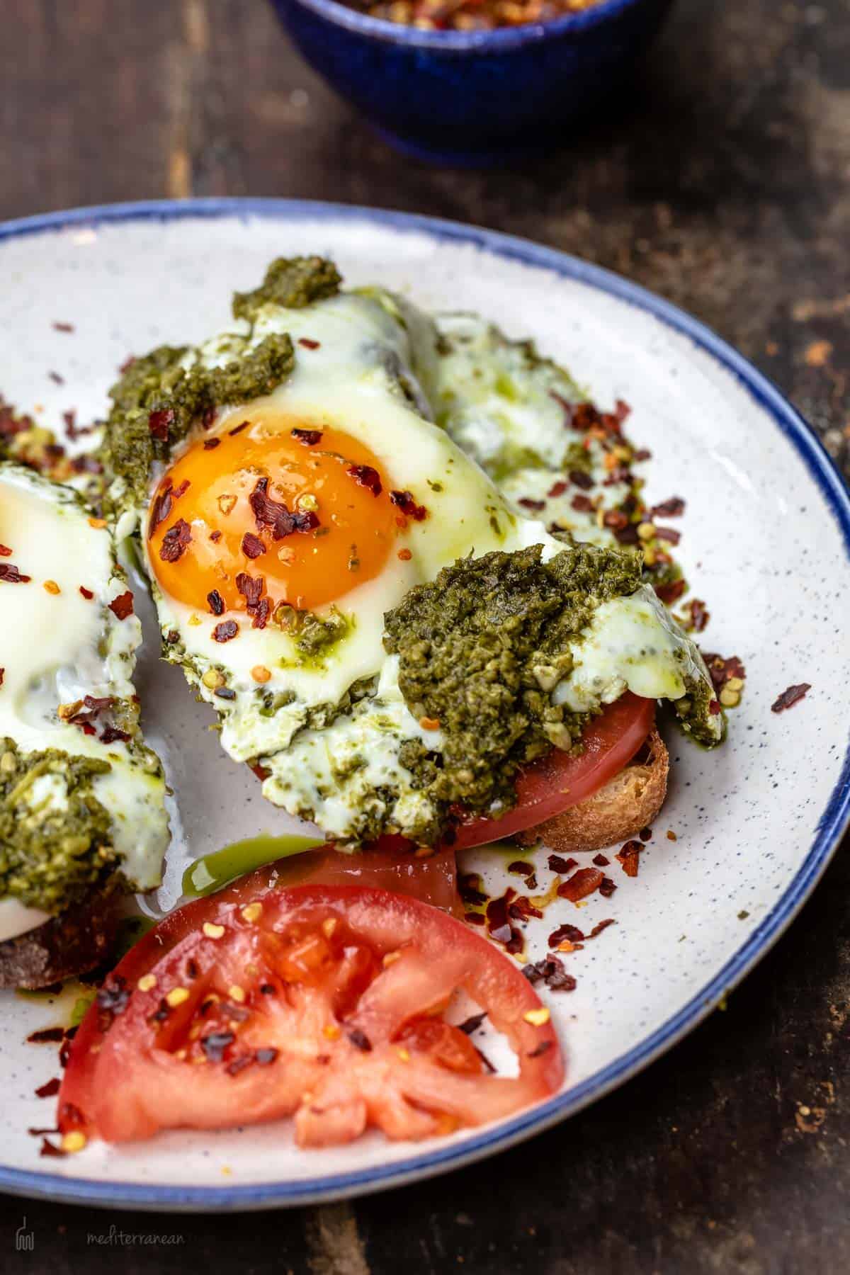 Eggs cooked sunny side with pesto served on a plate