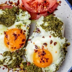Pesto eggs served on a plate with tomato slices