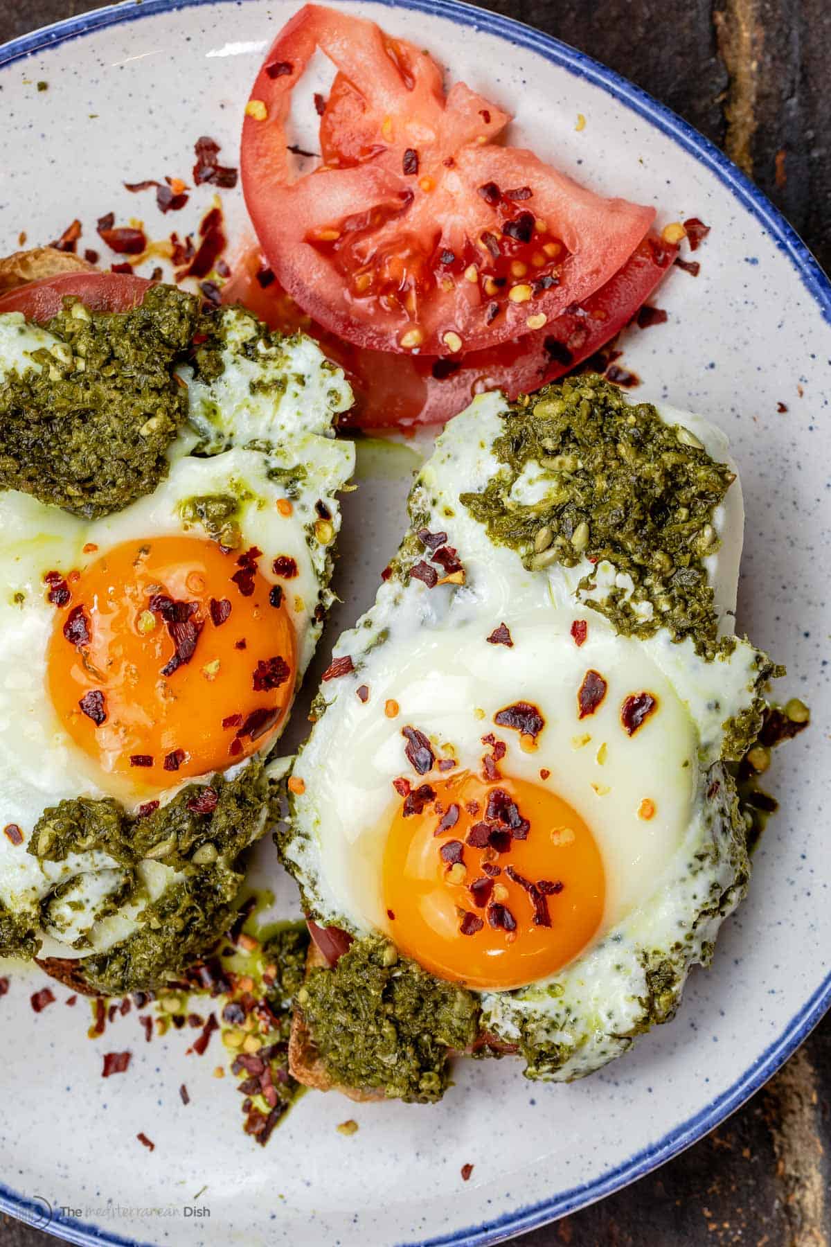 Pesto eggs served on a plate with tomato slices