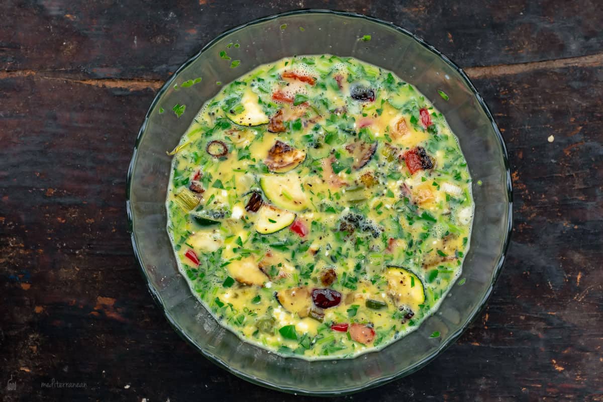 The Egg and Vegetable Mixture in a Glass Mixing Bowl on a Table