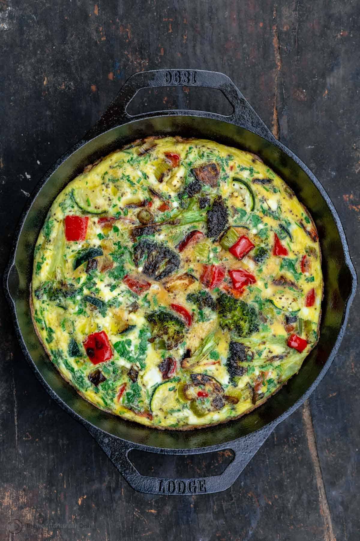 A Black Pan with Handles Containing a Freshly Baked Broccoli Red Pepper Frittata