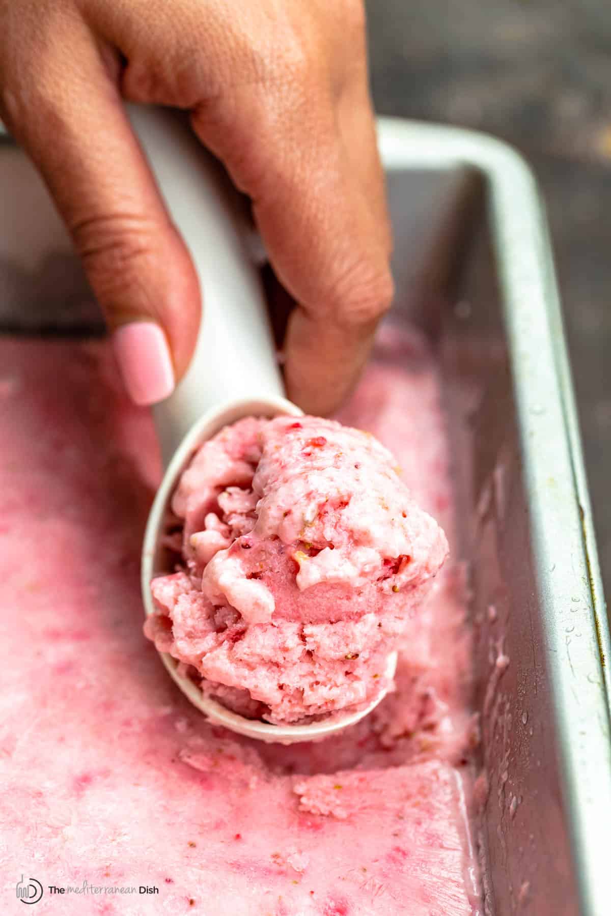 a hand holding ice cream scoop with frozen yogurt