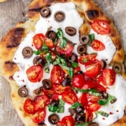 Grilled pizza with tomatoes, basil and olives