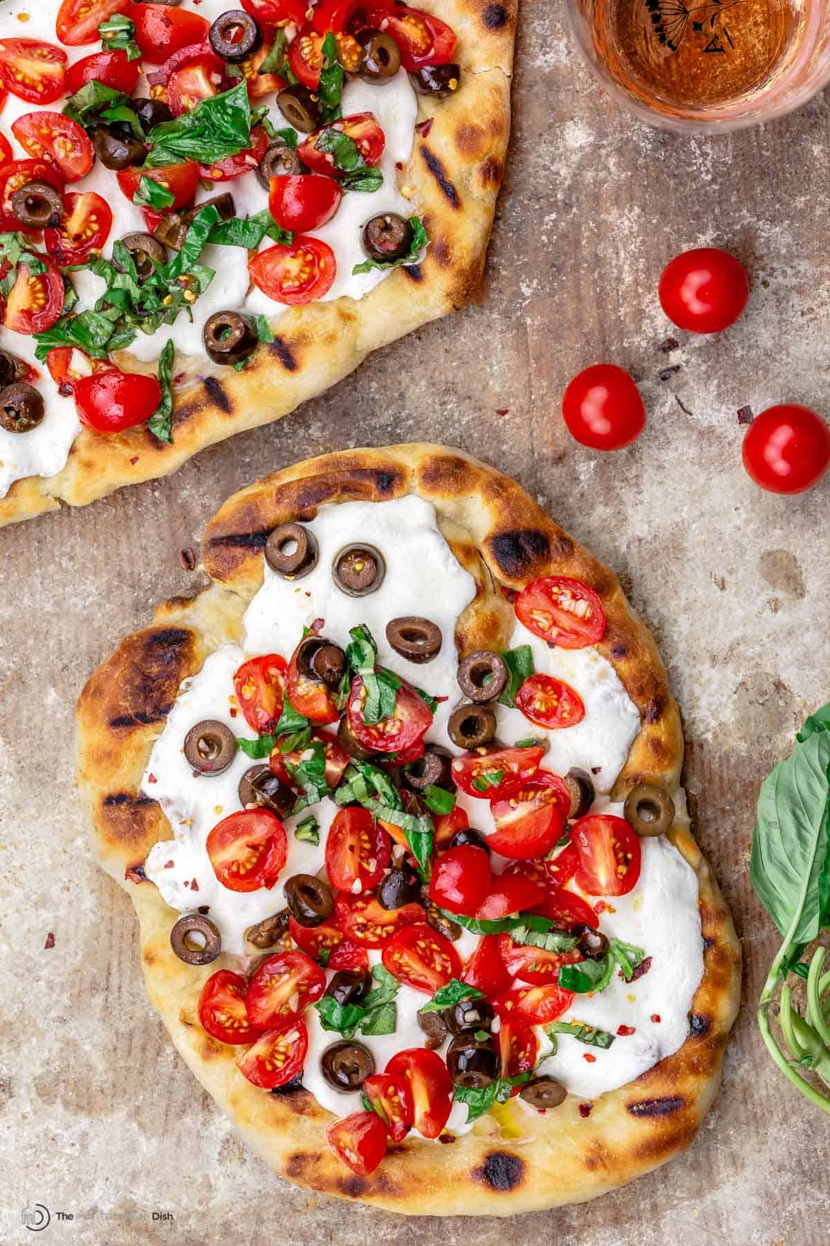 Grilled pizza with tomatoes, basil and olives