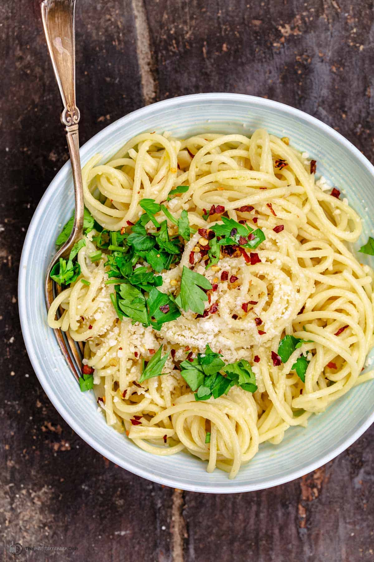 A bowl of pasta aglio e olio topped with parsley and parmesan