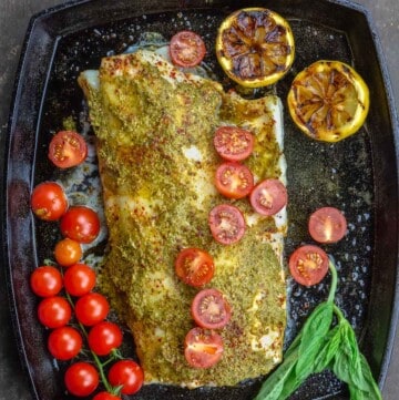 Baked sea bass with basil pesto, grape tomatoes and grilled lemon halves
