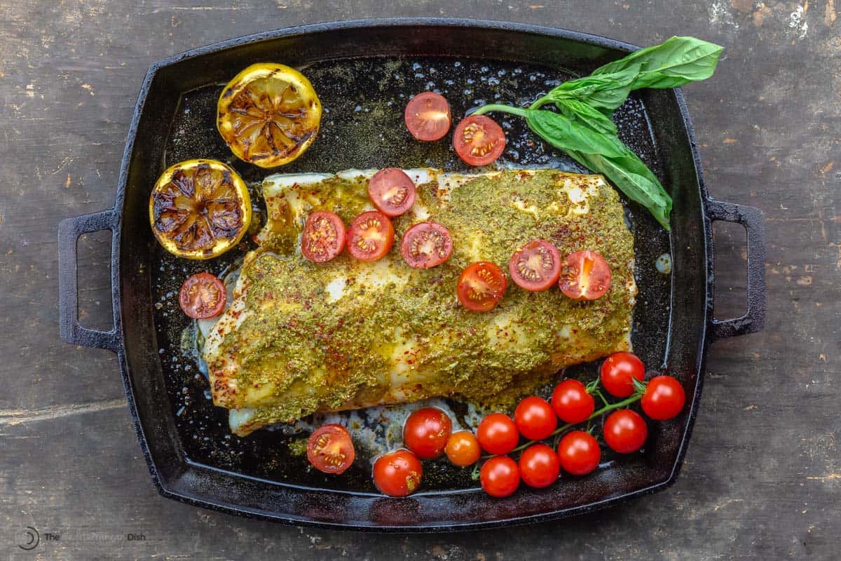 A baked sea bass fillet topped with pesto and grape tomatoes