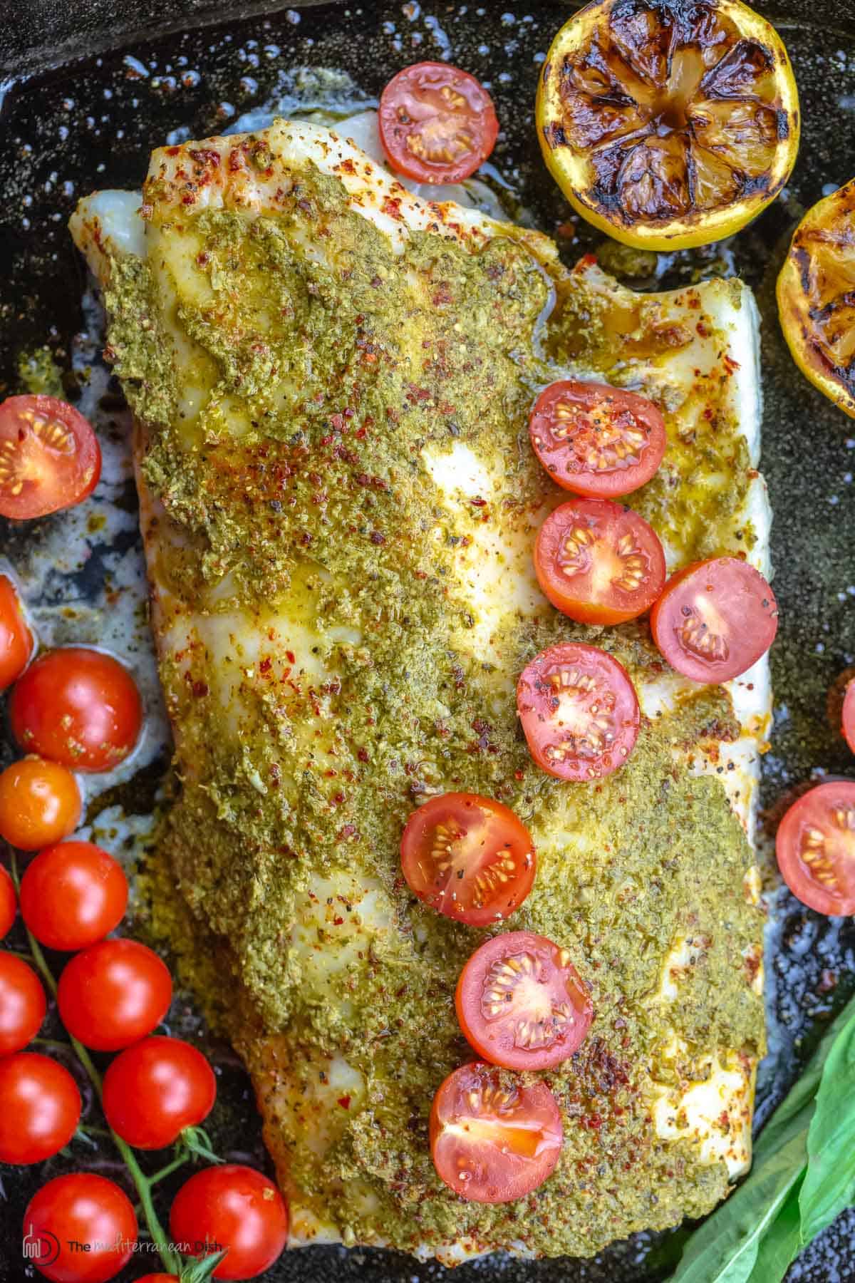 Baked sea bass topped with pesto and grape tomato halves