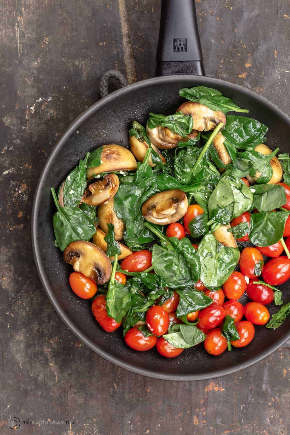 Mushrooms, spinach and cherry tomatoes in a skillet