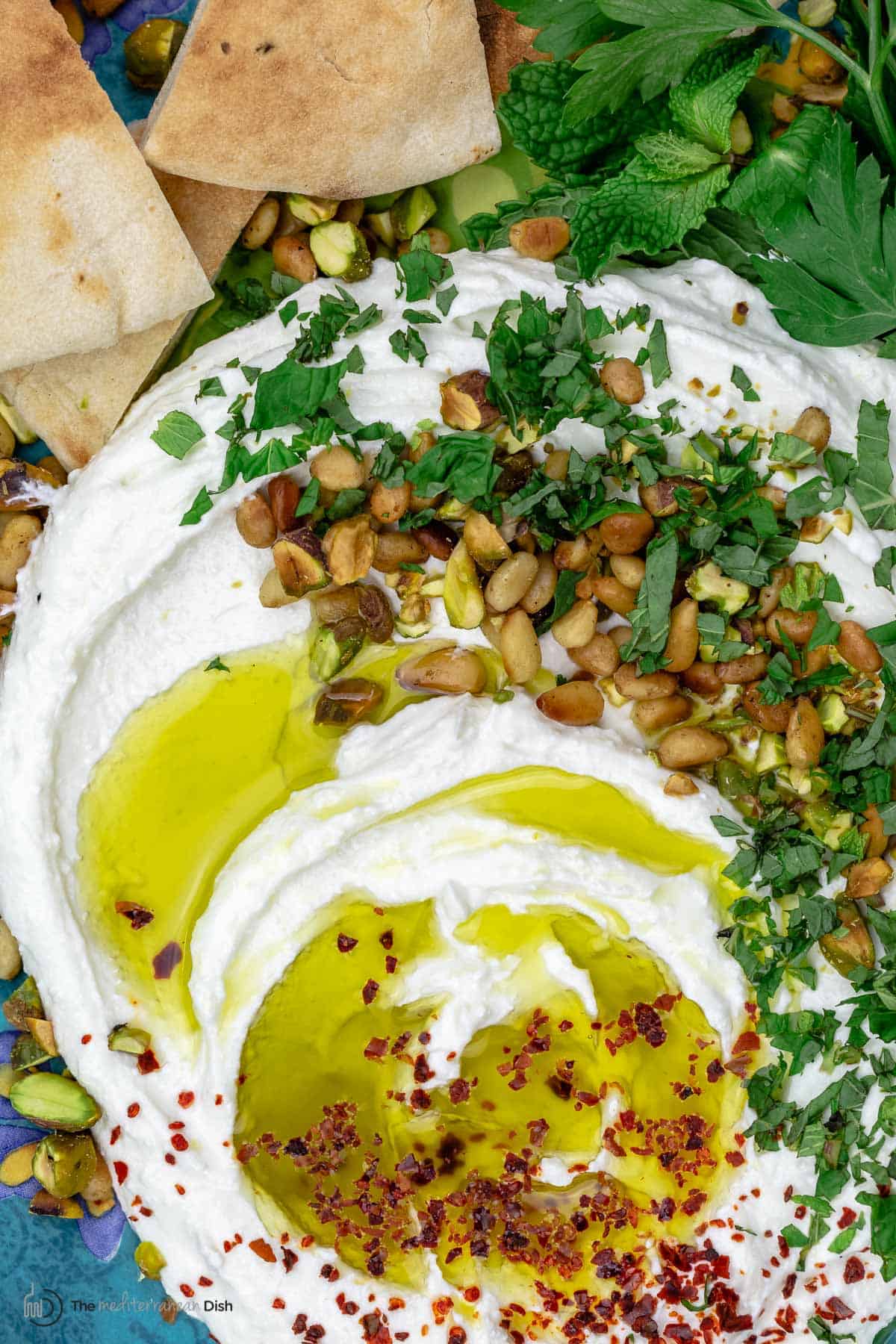 A close-up of whipped feta with olive oil, pine nuts, pistachios and herbs