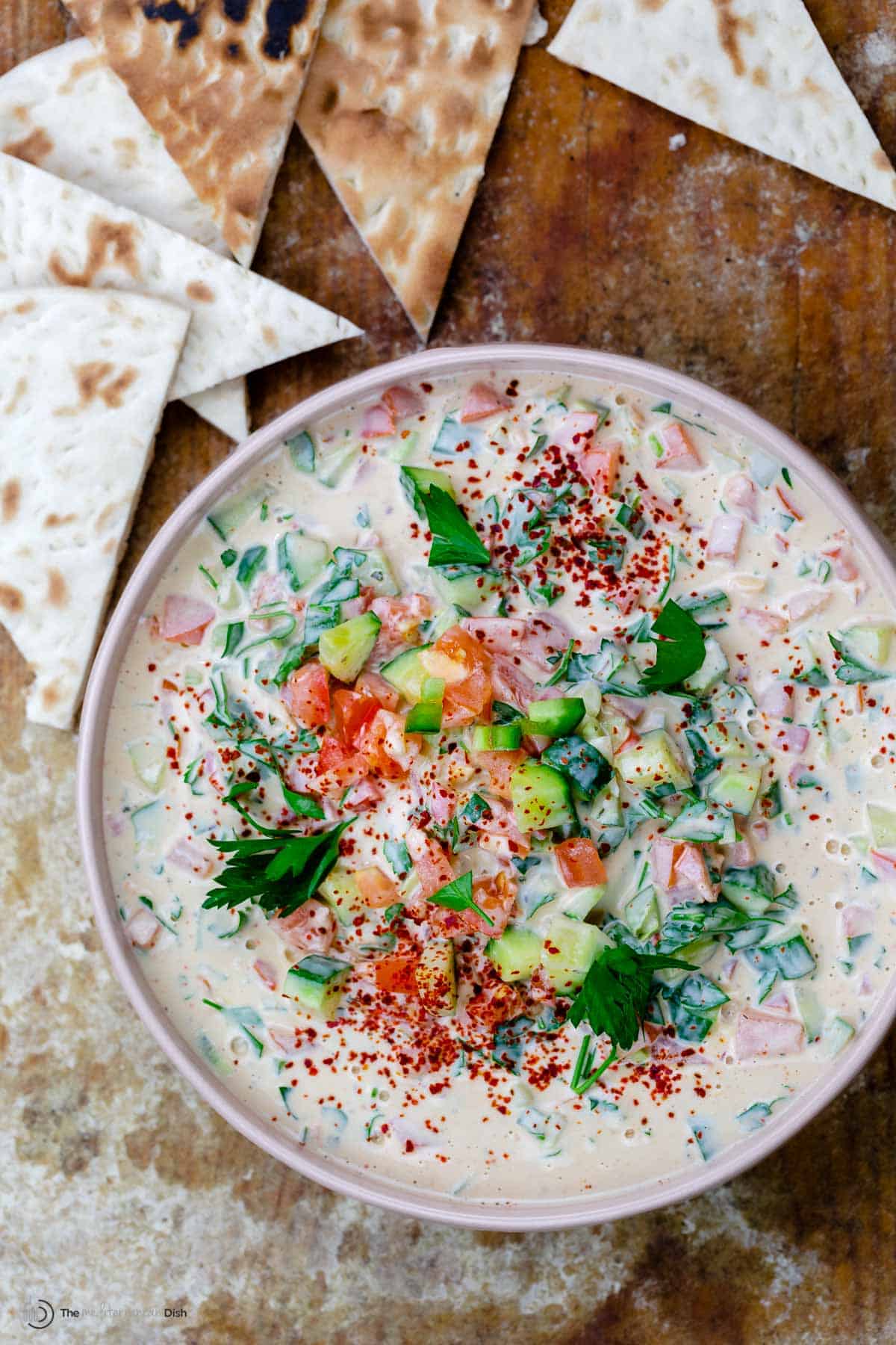 A bowl of cucumber and tomato tahini salad