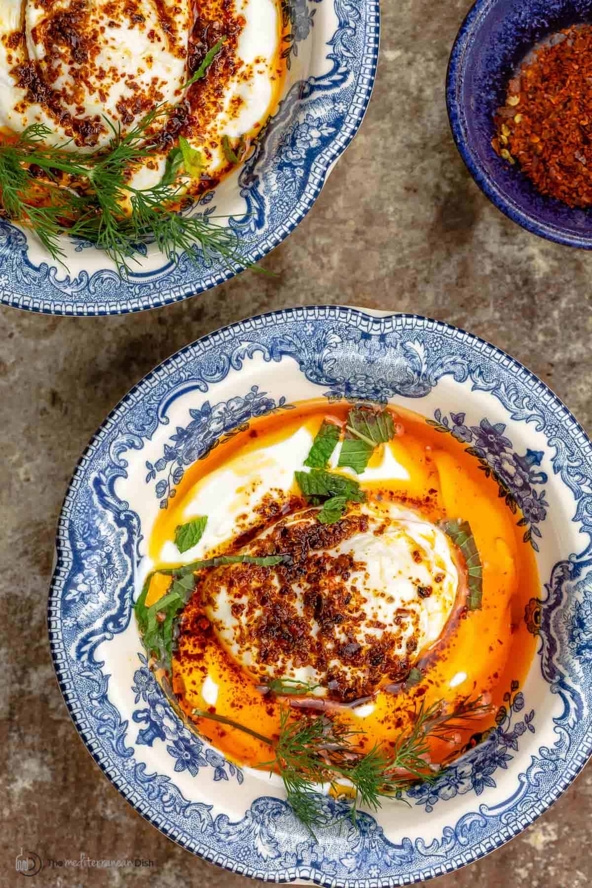 cilbir topped with aleppo pepper in a blue and white dish