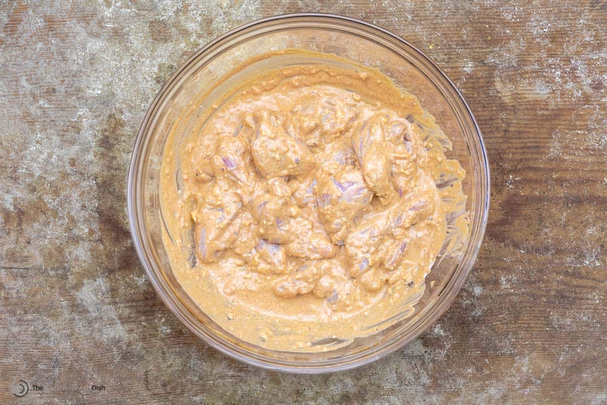 Chicken tawook marinating in a glass bowl