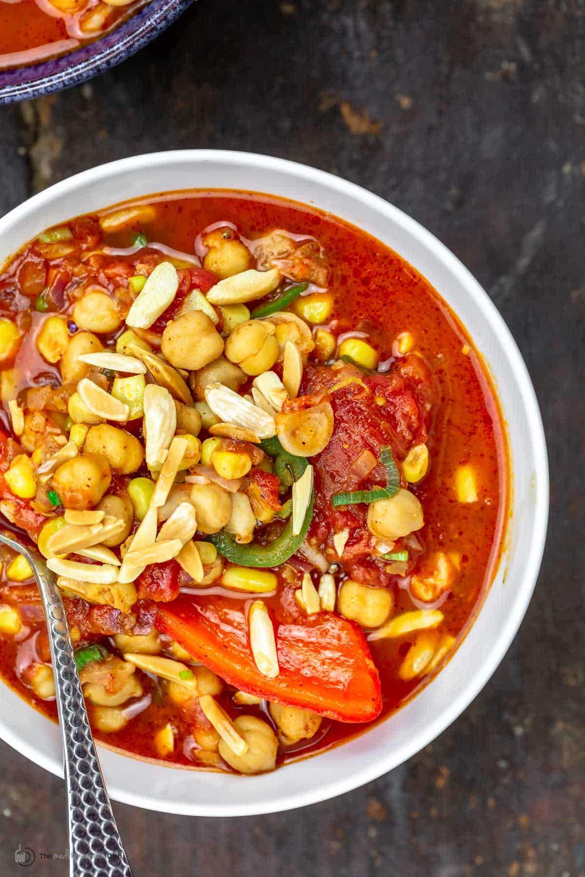 A big bowl of chickpea chili topped with toasted almonds