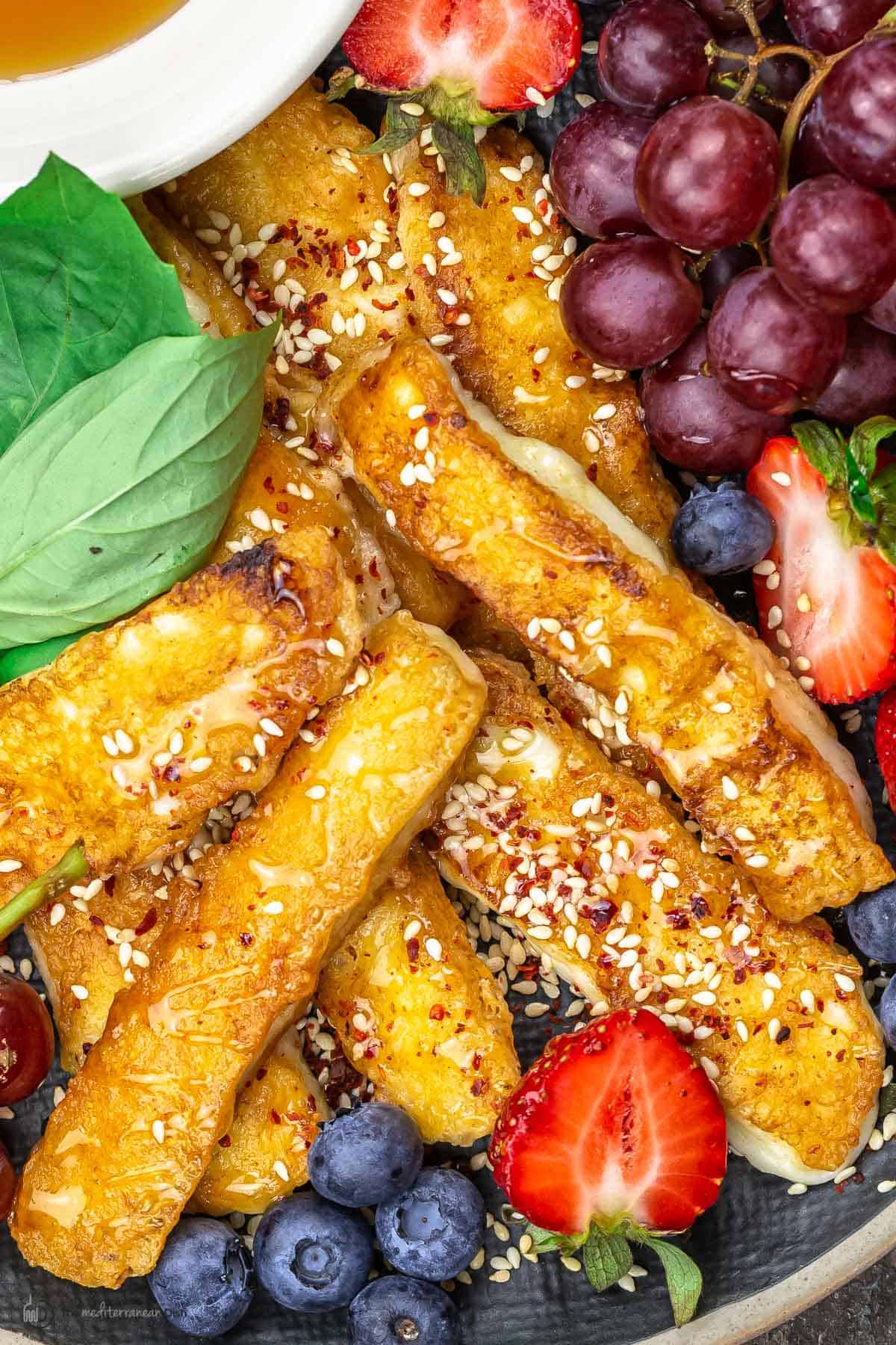 fried halloumi on a platter with fruit and honey