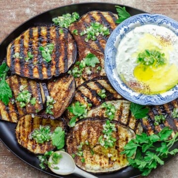 Mediterranean grilled eggplant slices on a plate with whipped feta dip