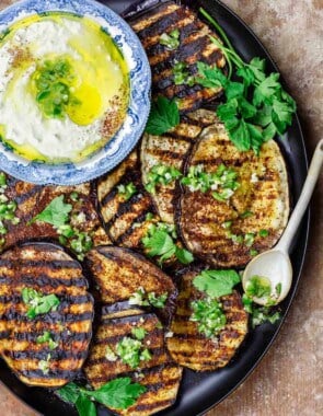 Mediterranean eggplant slices topped with infused olive oil with a serving dish of whipped feta