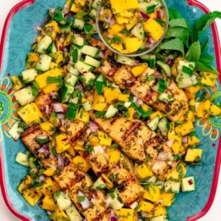 Grilled salmon served on a large plate with mango salad