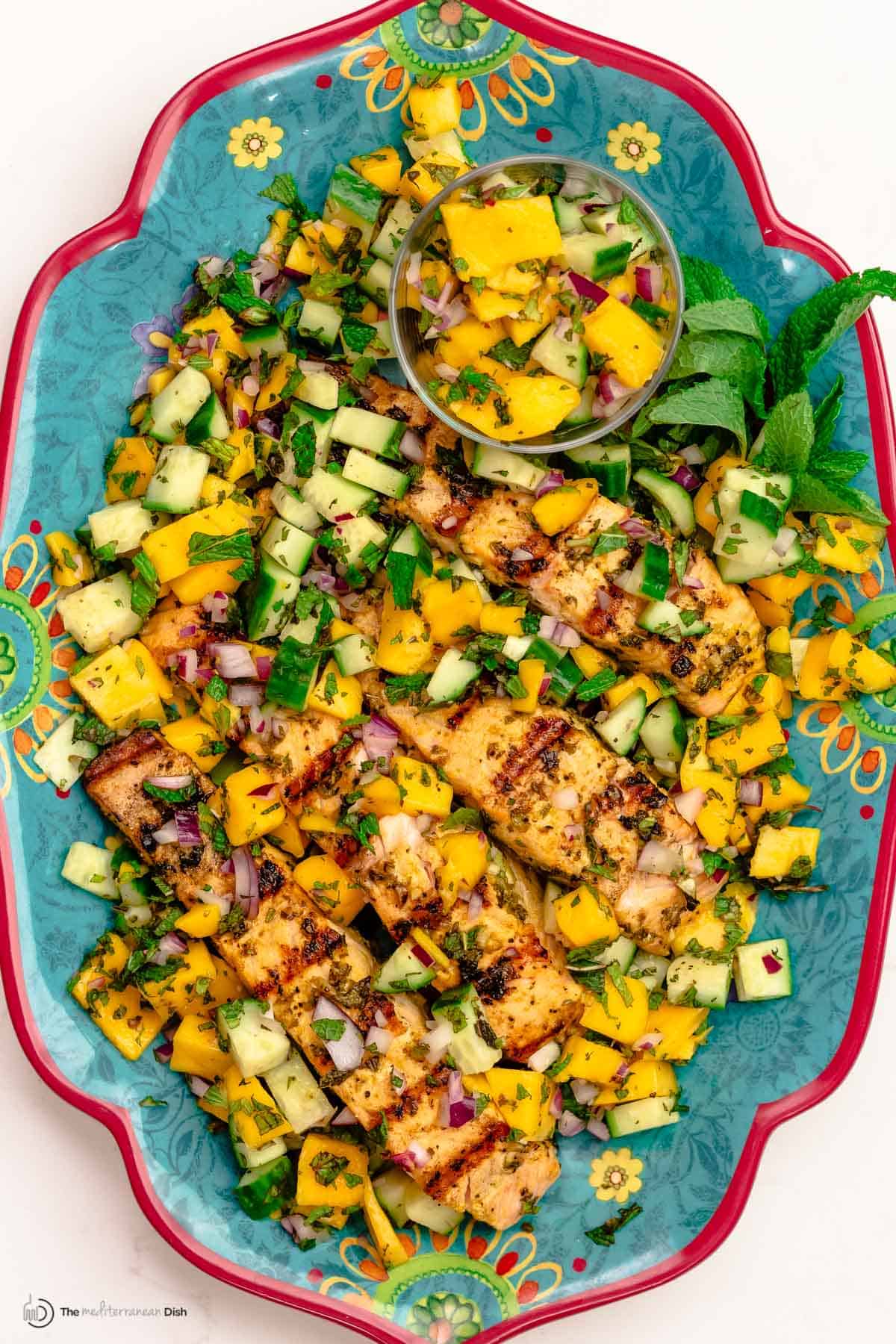 Grilled salmon served on a large plate with mango salad