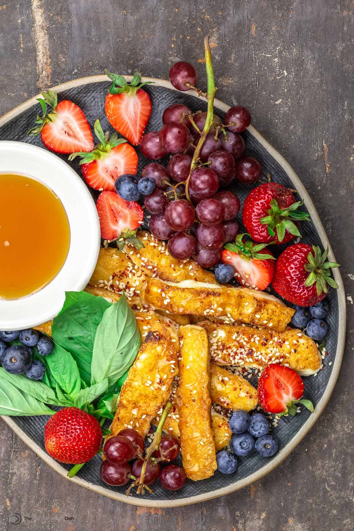 Halloumi fries on a serving plate with fruit and honey