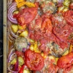 Close-up of baked meatballs with tomatoes and other vegetables in a sheet pan