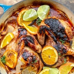 Roasted chicken with rosemary and citrus slices of orange and lime in a braising pan