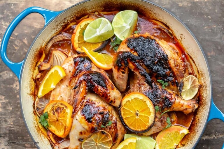 Roasted chicken with rosemary and citrus slices of orange and lime in a braising pan